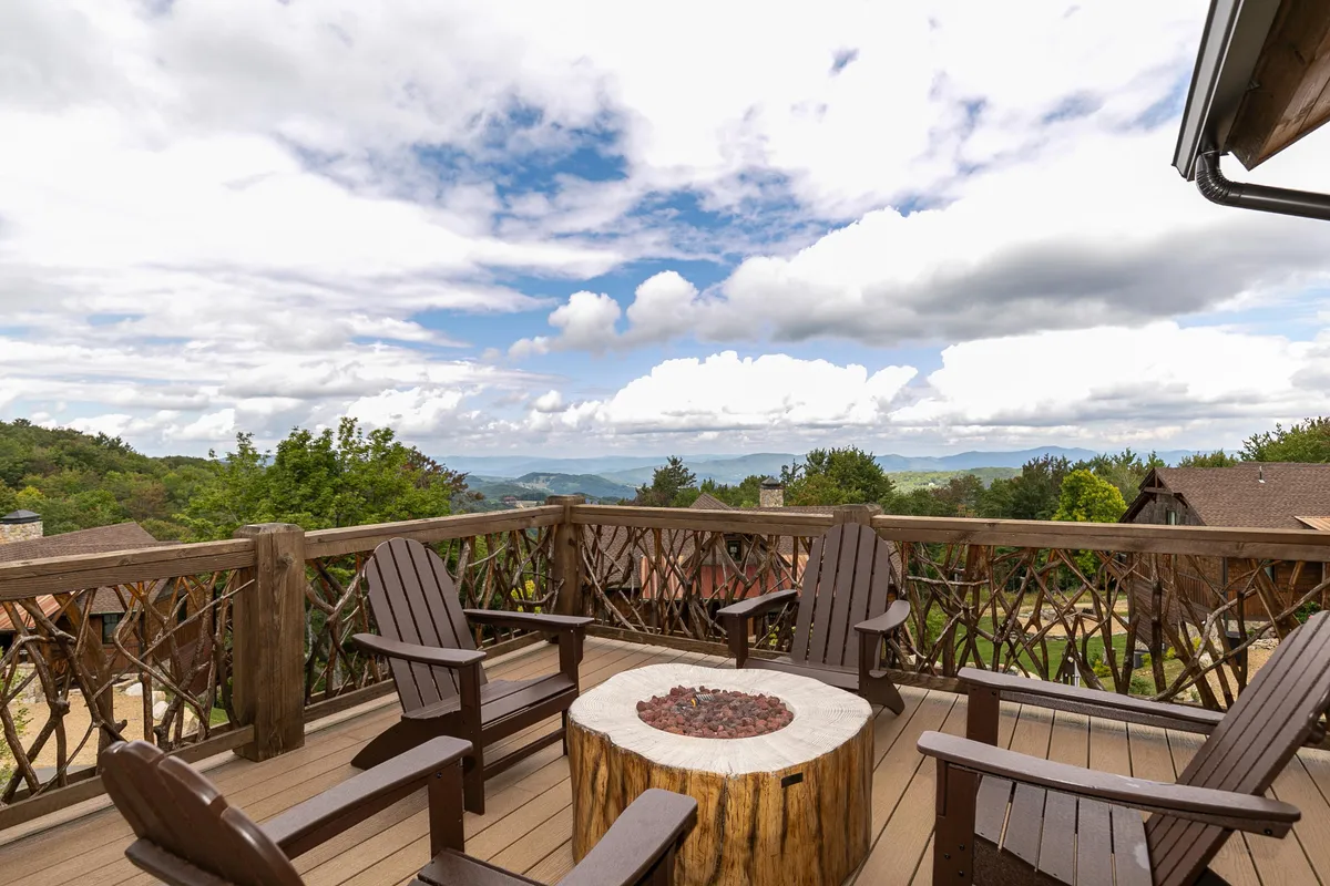 This image shows a cozy fire pit surrounded by wooden chairs with a breathtaking mountain view in the background. The setup suggests a perfect spot for gathering, sharing stories, and enjoying the outdoors with family.