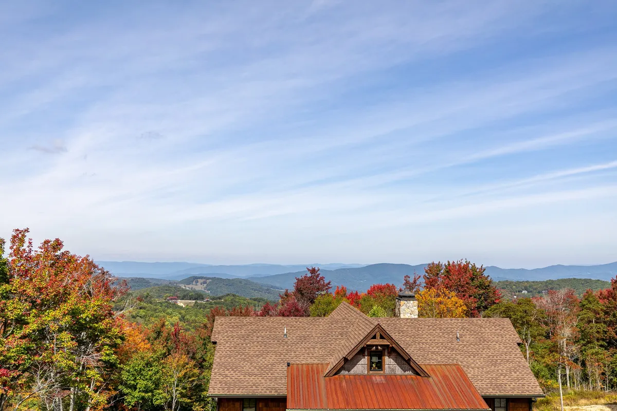 A wide view of the house nestled among tall trees with distant mountain views. The surrounding area offers ample space for nature walks, outdoor exploration, and enjoying fresh mountain air—activities both guests and their dog companions can enjoy.